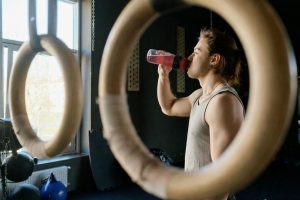 Man dricker ur sportflaska vid träningsringar för optimal hydrering.