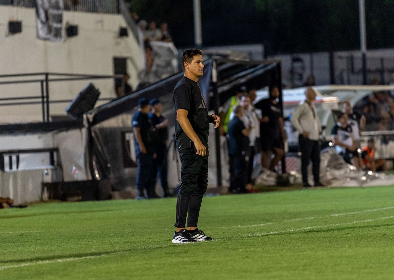 Tränare står vid sidlinjen på en upplyst fotbollsplan